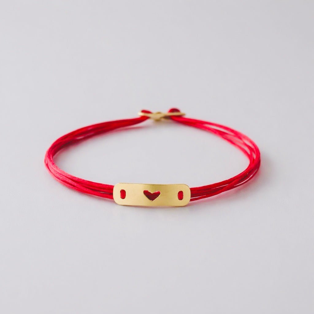 Handcrafted 14K gold plate bracelet with a hand-sawn heart showing red thread.